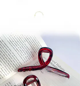 Macro shot of large burgundy tortoiseshell hair claw clip on a French vintage style book