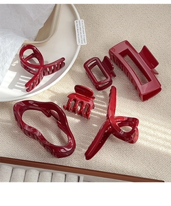 Detailed close-up of 5 red geometric hair claw clips set on a warm beige background