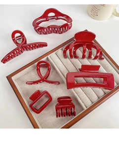 Detailed set of seven deep red resin hair claws in various geometric designs on display