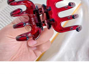 Macro detail of red vintage resin shark hair claw clip showing a strong metal spring structure