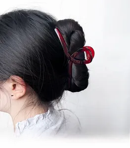Detail of a large dark red resin claw clip securing a French twist hairstyle on a woman