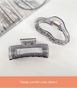Set of two transparent grey claw clips in geometric and wavy designs on white background