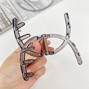 Translucent dark grey hair claw clip with cross-oval hollow design and golden metal spring