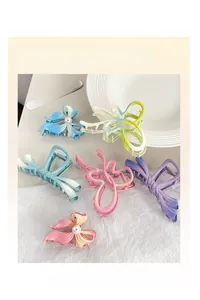 Detailed top view of pastel gradient butterfly hair clips with pearl accents on a plate