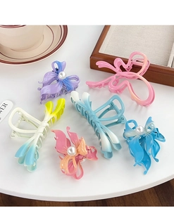 Detailed close-up of matte butterfly hair claws with pearls and metal springs in soft pastel tones