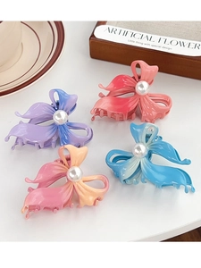 Detail view of four gradient butterfly hair claws with pearl center on a white surface