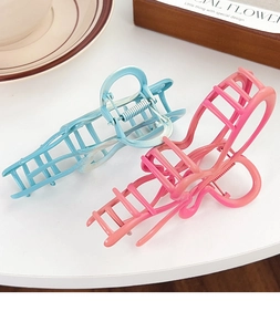 Detailed view of hollow geometric hair claws in matte blue and pink resin with springs