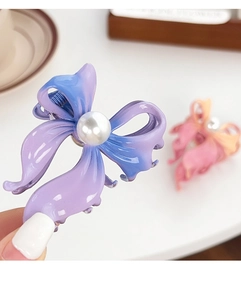 Detailed view of a purple gradient butterfly hair claw clip with a large white pearl center
