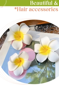 Close-up of three realistic plumeria flower hair clips with yellow gradient on a magazine