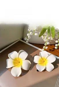 Close-up of two realistic white and yellow plumeria flower hair claws with matte finish