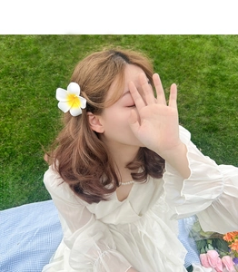 Outdoor shot of a model wearing a frangipani flower hair claw clip with a summer vibe