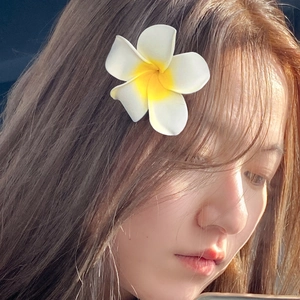 Elegant white and yellow plumeria flower hair claw clip worn on a woman's side profile