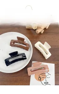 Classic square acrylic hair claws in brown, cream, black, and pink colors on a tray