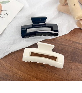Detail of square acrylic hair claws in black and cream beige for elegant daily styling