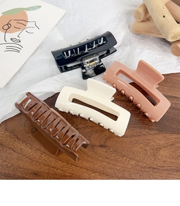 Detailed view of four large square acrylic hair claws in black, brown, cream and pink