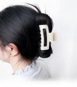 Detail view of a beige matte acrylic hair claw clip used for an elegant bun hairstyle