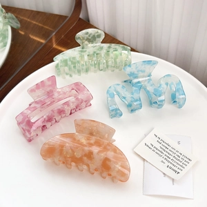 Elegant marble pattern hair claws in pastel colors displayed on a white ceramic plate