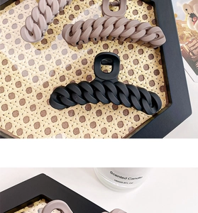 Detailed top view of matte chain link hair claws in various earthy tones on a tray