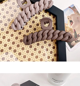 Detail of matte chain claw clip in dusty purple and dark coffee tones for hair styling