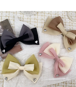 Détail de barrettes nœuds en organza multicouches avec strass en cœur en quatre couleurs