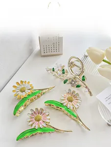 Detail of four metal daisy hair claws with enamel finish, pearls, and crystals in gold