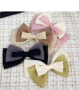 Détail de barrettes à nœuds en mousseline scintillante de couleurs variées sur tweed
