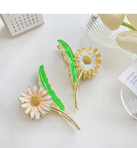Detail of daisy flower hair claws with enamel leaves and gold alloy finish for women