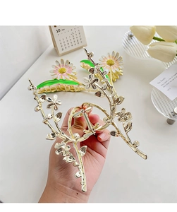 Detail of large gold alloy daisy hair claw clip with floral pattern and shiny rhinestones