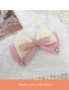 Détail d'une pince à cheveux à double nœud avec strass en cœur et tissu en organza