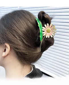 Detail of a large daisy claw clip with pink gradient petals and green leaf handle