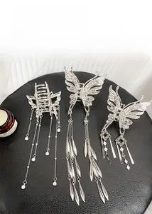 Vue détaillée des pinces à cheveux papillon argentées avec longs pompons et perles