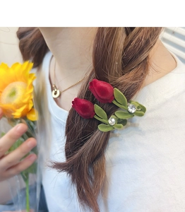 Détail de la pince à cheveux tulipe floquée rouge avec strass sur une queue de cheval