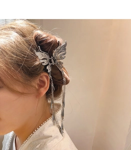 Détail d'une pince à cheveux papillon argentée avec de longs glands élégants