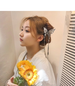 Détail de la pince à cheveux papillon argentée avec ailes évidées et longs pompons