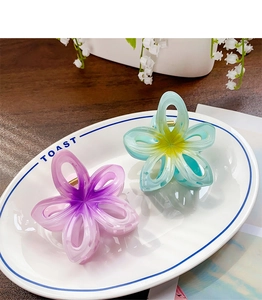 Détail de pinces à cheveux en forme de fleur dégradé bleu et violet sur un plateau