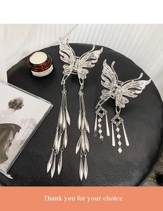 Détail de pinces à cheveux papillon argentées élégantes avec de longs glands sur cuir