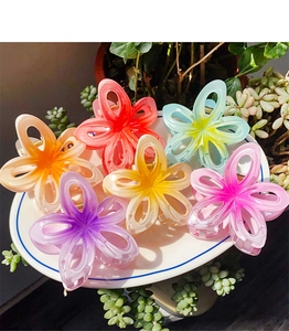 Détail de six pinces à cheveux en forme de fleurs dégradées sur un plateau blanc