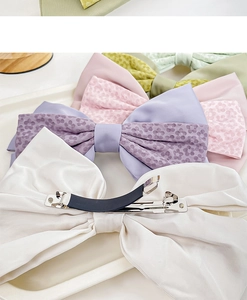 Detailaufnahme von Satin-Haarschleifen mit silbernen Metall-Federclips und Anti-Rutsch-Pads