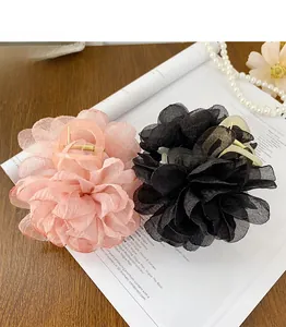 Détail de pinces à cheveux à fleurs 3D roses et noires sur un décor de table élégant