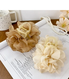Détail de pinces à cheveux florales en tissu crème et champagne avec ressorts dorés