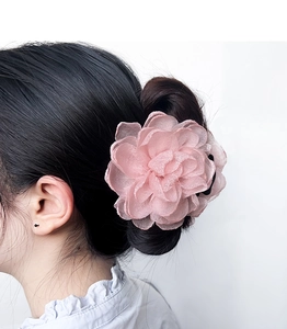 Détail d'une élégante pince à cheveux en organza rose lotus sur un chignon féminin
