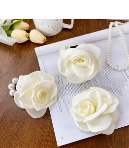 Detailed macro view of white satin 3D rose hair accessories with elegant pearl charms