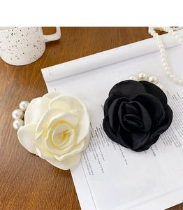 Detailed close-up of handmade fabric rose hair pins with pearls on a magazine background
