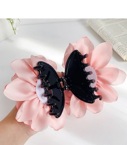 Detail of a large pink flower hair claw clip with multi-layer fabric daisy petals