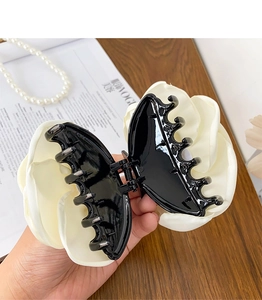 Close-up of large cream satin fabric flower hair claw clip with black plastic teeth