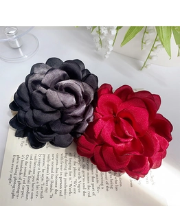 Macro detail of large rose flower hair clips in elegant black and burgundy satin fabric