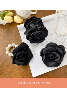 Detailed set of black silk rose hair clips and pearl elastic tie on a wooden table