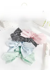 Close-up of four wavy pattern fabric bow hair scrunchies in pastel colors and black