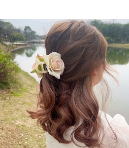 Détail d'une grande pince à cheveux rose en tissu portée dans un chignon décontracté