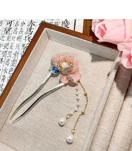 Vue détaillée d'un pic à cheveux en métal avec pétales roses, perles et pompons